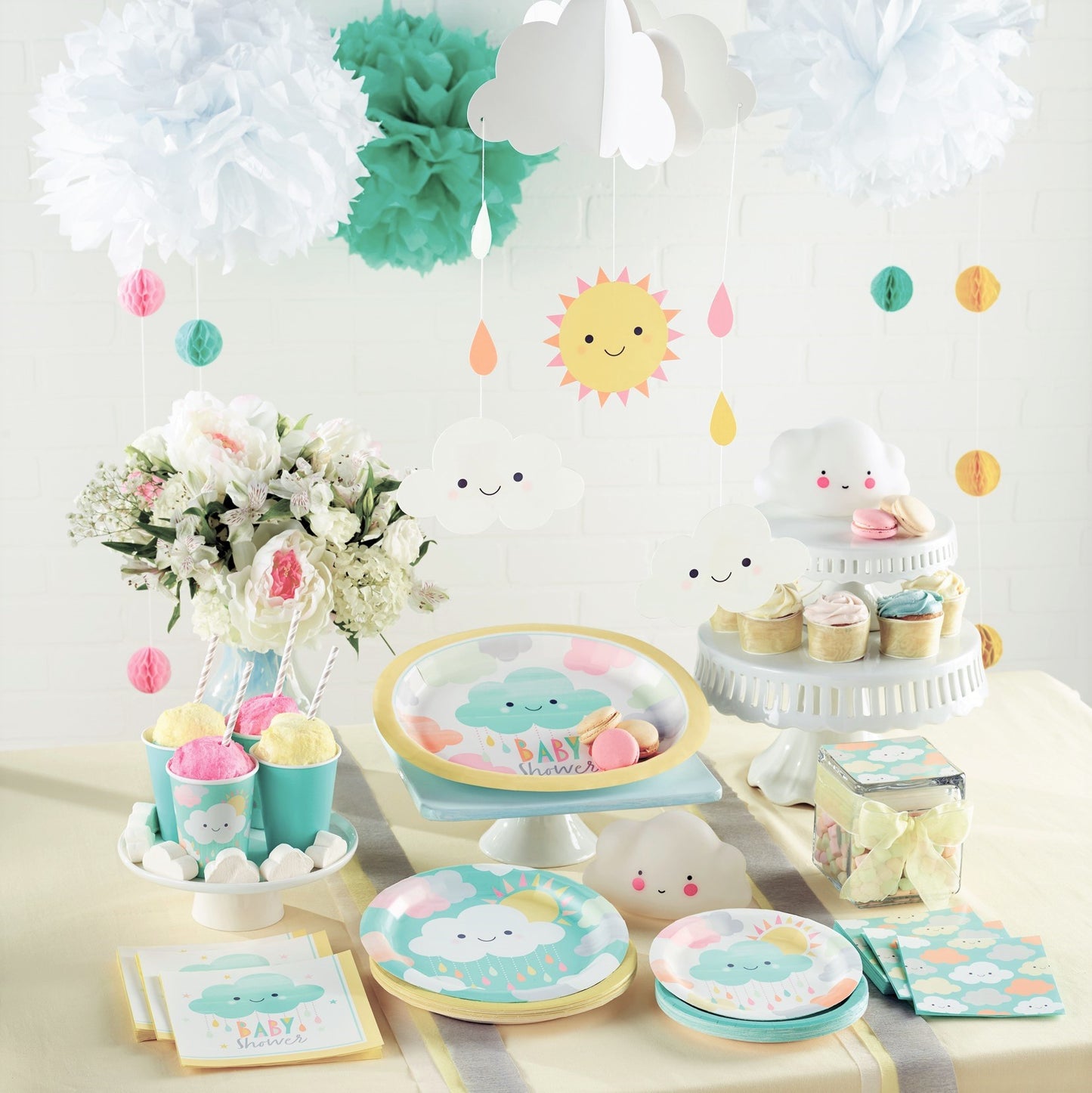 baby shower party range in unisex pastel colours laid out on a table. Decorated with clouds, raindrops and sunshine